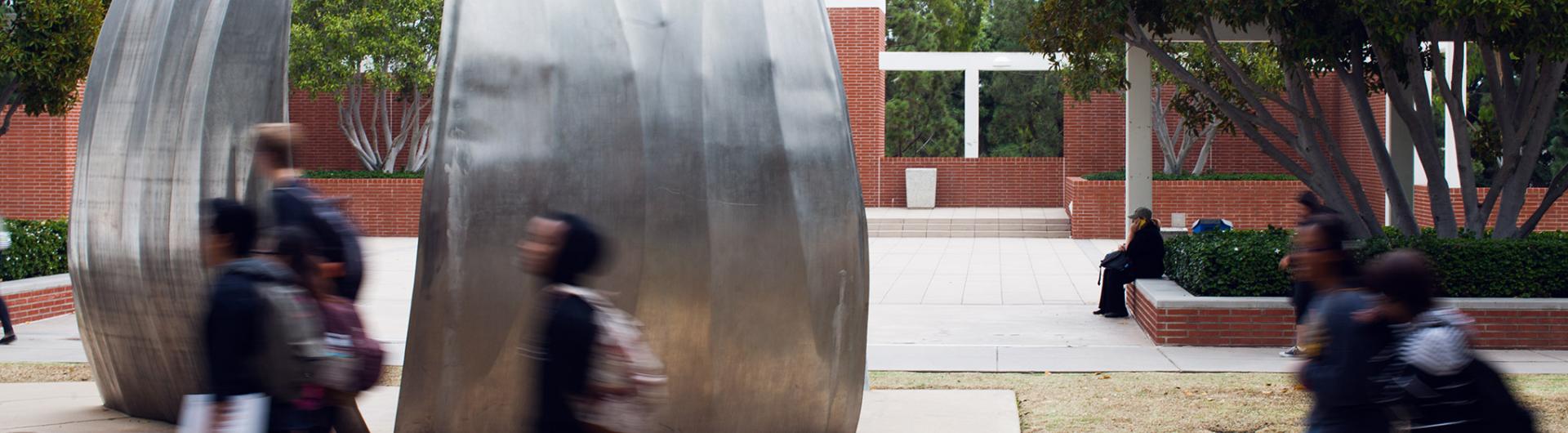 Students walk past a well-known campus Sculpture